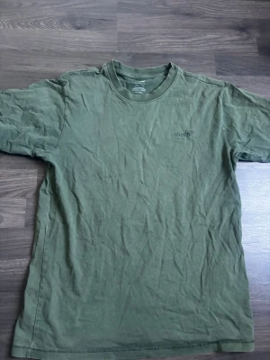 Grön vintage t-shirt från Levi's - Säljer en grön vintage fit t-shirt från Levi's i storlek XS. T-shirten har klassisk rund hals, korta ärmar och diskret Levi's-logga på bröstet. Tillverkad i mjuk bomull som känns skön mot huden. Perfekt för en avslappnad och stilren look.