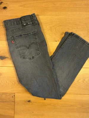 Levi’s 514 W36 L30 - Klassiska Levi’s 514 i gråtvättad denim med skön, urblekt patina och naturliga nyansskiftningar. Straight/slim fit – smalare passform i benen men ändå bekväm och avslappnad.  Skick: Fint begagnat skick med generell tvättslitning som ger jeansen karaktär. Inga hål eller skador.  Detaljer:  * Modell: 514, straight/slim fit * Färg: Grå, tvättad denim * Storlek: W36 L30 (enligt innerbrickan) * Läderpatch bak samt röd Levi’s-tab på bakfickan * Knappgylf * 100% bomull