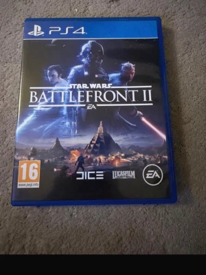 Star Wars Battlefront II PS4 spel - Star Wars Battlefront II till PS4 är ett actionfyllt spel med ikoniska karaktärer och episka strider från Star Wars-universumet. Omslaget är blått med motiv från spelet och logotyper från DICE, Lucasfilm och EA. Spelet är i fysisk form och har PEGI 16-märkning.