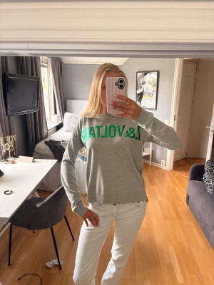 Grå sweatshirt från Zadig & Voltaire - Står att det är storlek 16/M. Jag skulle bedöma det som storlek S. Snygg grå sweatshirt från Zadig & Voltaire med grönt tryck över bröstet. Tröjan har rund halsringning och långa ärmar. Perfekt till jeans eller kjol för en avslappnad look.