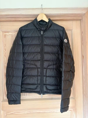 Moncler acorus - svart  - Snygg svart dunjacka från Moncler med quiltad design och hög krage. Size 5 sitter som L. Mycket bra skick har nästan aldrig varit använd.