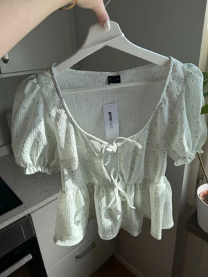 Kortärmad topp - Söt topp från GinaTricot, 2 knyten fram. Mintfärg 💚 Ena klädbandet (sista bilden) har lossnat men ingenting som påverkar utseendet av plagget  Storlek; XS Skick; Ny med prislapp Material; 98% polyester, 2% elastan  #sommar #topp #blommig #scandi #ginatricot