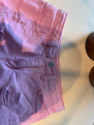 Rosa slitna jeanskjol - Säljer ett par ljusrosa jeanskjol med slitna detaljer och fransig kant. Helt ny alldrig använd då den var för liten💕
