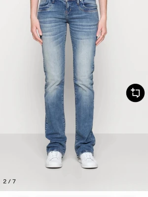 Blå bootcut jeans - Säljer ett par ljusblå bootcut jeans med snygga slitningar och tvättade detaljer. Jeansen har klassisk femficksmodell och normal midja. Perfekta för dig som gillar en avslappnad men trendig look.