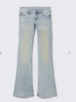Ljusblå bootcut jeans - Säljer ett par ljusblå bootcut jeans med snygga slitningar och blekta partier framtill. Jeansen har låg midja och utsvängda ben. W 26, L 30.