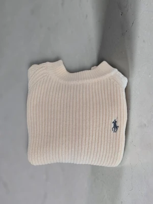 Vit stickad tröja från Ralph Lauren - Klassisk vit stickad tröja från Ralph Lauren med ribbad struktur och rund hals. Passa på o köpa nu när det börjar bli lite kallare ute. 