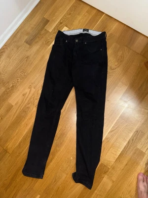 Svarta jeans från Sams Black M - Snygga svarta jeans från Sams Black i storlek M. Klassisk femficksmodell med raka ben och normal midja. Jeansen har en enkel design utan slitningar eller dekorationer, vilket gör dem lätta att matcha till olika stilar. Perfekta för dig som gillar en clean look.