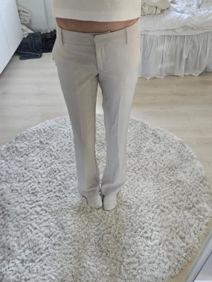 Beiga kostymbyxor från Bik Bok - Snygga beiga low waist kostymbyxor från Bik Bok med raka ben. Byxorna har hällor för skärp, diskreta sidofickor. Perfekta för en clean och stilren look.