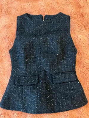 Mörkblå glittrig byxdress - Snygg mörkblå ärmlös byxdress med glittrande paljetter och två dekorativa fickor framtill. Materialet är strukturerat och ger en exklusiv känsla. Dragkedja bak för enkel påklädning. Perfekt för dig som vill sticka ut med stil. Helt ny, ordinarie pris 239.
