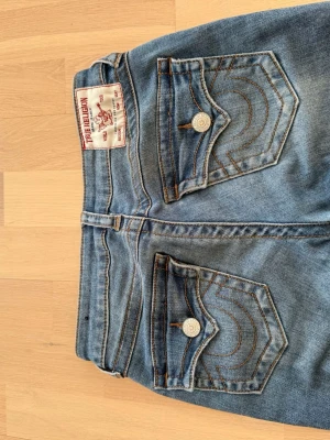 Blå raka jeans med hög midja - Säljer ett par klassiska blå jeans med botcut. Jeansen har fem fickor, bälteshällor och snygga slitningar framtill för en trendig look. Perfekta till en avslappnad stil och passar till det mesta i garderoben. På den sista bilden så ser man att jeansen har ett litet hål i skrevet, men de syns inte på💗💗