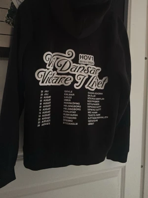 Svart Hov1 hoodie  - Säljer en svart hoodie med stor vit text på ryggen från sista  Hov1s turné  den är i bra skick nästan som ny!❤️Hoodien har huva och klassisk passform. Perfekt  vill visa ditt stöd för Hov1. 