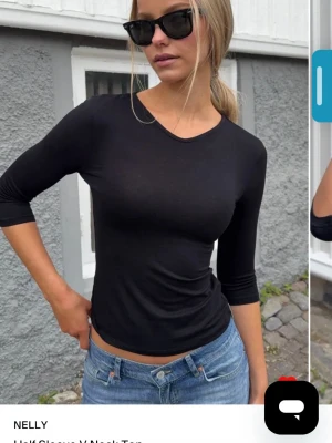 Svart topp med trekvartsärm från Nelly - En stilren svart topp från Nelly med trekvartsärm och rund halsringning. Toppen har en slim passform och är tillverkad i ett mjukt, stretchigt material som sitter snyggt på kroppen. Perfekt att matcha med jeans eller kjol för en clean look.