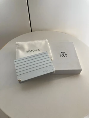  Rimowa korthållare - Snygg och stilren plånbok från Rimowa i silverfärgad metall med horisontella ränder. Kommer med originalförpackning och tygpåse. Perfekt för kort och småsaker, med modern och minimalistisk design.