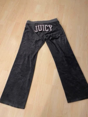 JUICY byxor vintage - Mjukisbyxor i mörkgrå velour med bred resårmidja och dragsko. På baksidan finns det ikoniska JUICY-trycket i stora bokstäver.  Mått på sista bilderna🌟