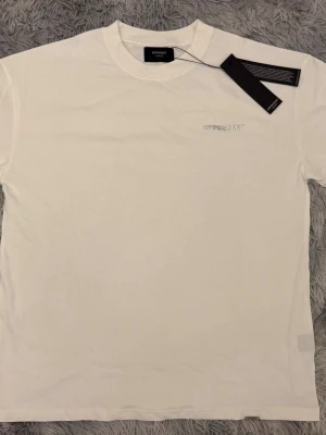 Vit t-shirt från Represent - Snygg vit t-shirt från Represent med diskret logga broderad på bröstet. Klassisk rund hals och korta ärmar. Tillverkad i mjuk bomull som känns skön mot huden. Perfekt basplagg för en clean och stilren look.
