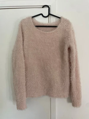 Ljusrosa fluffig stickad tröja - Supermjuk och fluffig stickad tröja i ljusrosa färg. Tröjan har rund halsringning och långa ärmar. 