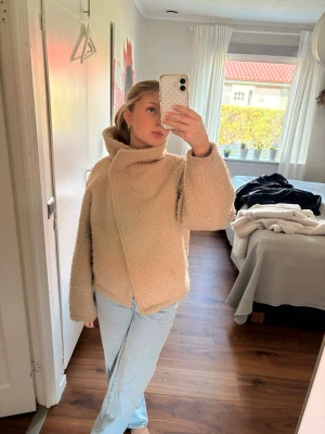 Beige teddyjacka med hög krage - Supermjuk och fluffig teddyjacka i beige med oversized passform och hög krage, går att knäppa som på tredje bilden med. Så himla fin men vill köpa nytt därför säljer jag förra säsongens🥰🥰🥰