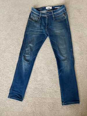 Replay Anbass jeans blåa - Säljer ett par blåa replay anbass i bra skick de har en liten slitning på vänster lår men det gör bara jeansen snyggare enligt mig. Storleken är från början  27, 32 men de är uppsydda till 27, 30. Jeansen är i replays hyperflex material vilket gör de väldig sköna att ha på sig. 