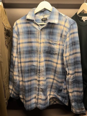 Blåvit skjorta från Replay - Snygg rutig skjorta i blått och vitt från Replay. Skjortan har klassisk krage, knäppning framtill och en bröstficka med liten röd detalj. Perfekt för en avslappnad och trendig stil. Använd 3 gånger och är precis som en helt ny. Inte helt min stil så därför säljs den. Nypris 2500kr mitt pris 1100.