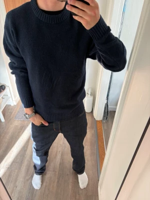 Mörkblå stickad tröja - En enkel och stilren mörkblå stickad tröja med rund halsringning och ribbade muddar vid ärmslut och nederkant. Perfekt för dig som gillar en clean och klassisk look. Passar till det mesta och är superenkel att matcha.
