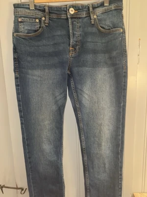 Blå raka jeans med slitningar - Snygga blå jeans med raka ben och lätt slitna detaljer framtill. Jeansen har klassisk femficksdesign och kontrastsömmar. Materialet är denim i bomull med en skön känsla. Perfekta till en avslappnad stil.