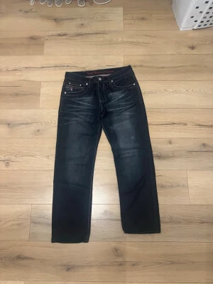 Tommy Hilfiger  - Snygga mörkblå jeans med raka ben och tydliga kontrastsömmar. Jeansen har fem fickor, dekorativa slitningar och broderad detalj vid fickan. Perfekta för en avslappnad och trendig stil.