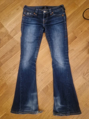 Lågmidjade true religion jeans - Mariblå låga bootcut true religion jeans i modellen Joey, storlek 25 (xs/s) har fållat upp dom så de passar mig som är ca 165! (Inga proffs sömmar) lite trasig längst nere vid hälarna men märks inte på och är annars i superbra skick! Orginalpris 1300!