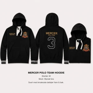 Svart Mercer Polo Team hoodie - Svart hoodie från Mercer Polo Team med broderade detaljer fram och bak, inklusive klubbmärke och stor siffra på ryggen. Huva med snörning och ribbade muddar vid ärmslut och nederkant. Klassisk känguruficka framtill.