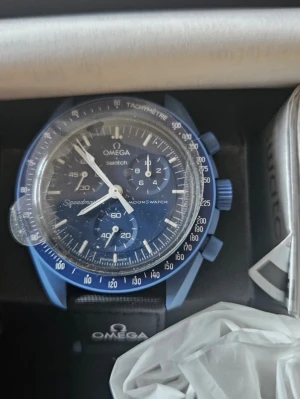 Omega x Swatch Speedmaster MoonSwatch Mission To Neptune. - Säljer en Omega x Swatch Speedmaster MoonSwatch Mission to Neptune. Klockan har en blå boett och matchande blå urtavla med vita detaljer och kronograf. Svart textilband med Omega-logga och Speedmaster-tryck. Perfekt för dig som gillar ikoniska klockor.