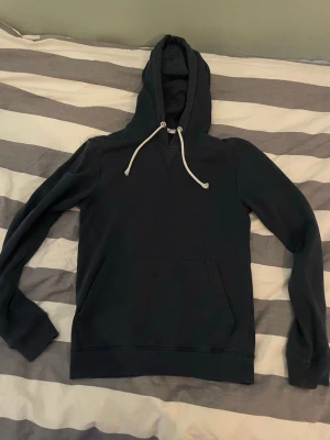 Pier one hoodie - En stilren svart hoodie med huva och vita dragsnören. Hoodien har en klassisk känguruficka framtill och långa ärmar. Perfekt för en avslappnad och bekväm look.