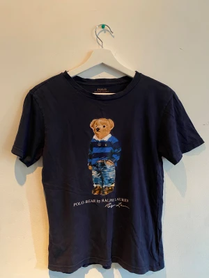 Mörkblå Polo Bear t-shirt - Säljer en mörkblå t-shirt från Ralph Lauren, Storleken är M (10-12 år) i barnstorlek. Passar längden 146-150cm 