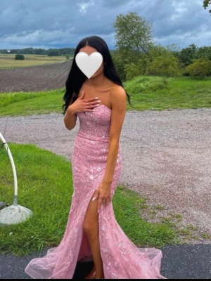 Rosa långklänning  - Säljer en elegant rosa långklänning med vacker spetsdetalj och blommigt mönster. Storlek 36. Använd en kväll