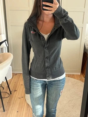 Hollister kofta  - Jättemysig mörkgrå kofta från Hollister i storlek M, mycket bra skick