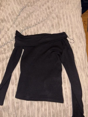 Svart offshoulder topp - Snygg svart offshoulder topp med lång ärm och tight passform. Perfekt för dig som vill ha en stilren och enkel look med en twist. Materialet känns mjukt och stretchigt, vilket gör den bekväm att bära. snygg o fin ❤️❤️