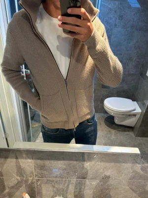 Beige ribbstickad ziptröja Massimo dutti - Säljer en beige ribbstickad tröja med dragkedja. Riktigt snygg och passar perfekt nu till hösten som ett ytterplagg eller som en vanlig tröja. Jag bär en strlk L på bilden och är 188cm vilket är ganska lagom. I övrigt bra skick och inga skador. Hör av er vid eventuella frågor och funderingar;)