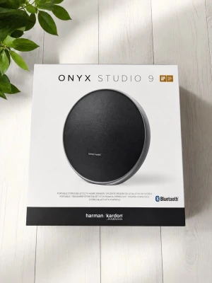 Harman Kardon Onyx Studio 9 högtalare - Snygg och modern trådlös högtalare från Harman Kardon, modell Onyx Studio 9. Rund design i svart med silverdetaljer och inbyggd Bluetooth. Perfekt för att streama musik trådlöst med kraftfullt ljud och stilren look.