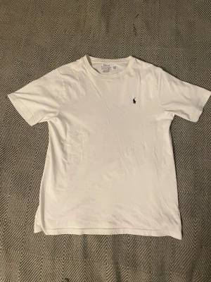 Vit Ralph Lauren T-shirt  - Vit T-shirt från Polo Ralph Lauren. Storlek kids large/14-16år/160cm. Mycket gott skick inga defekter. Stor i storleken, jag brukar ha xs och den är för stor för mig. Skulle därför säga att den ungefär motsvarar small. Skriv gärna vid minst fundering! Postar inom 24 timmar med PostNord eller Instabox!