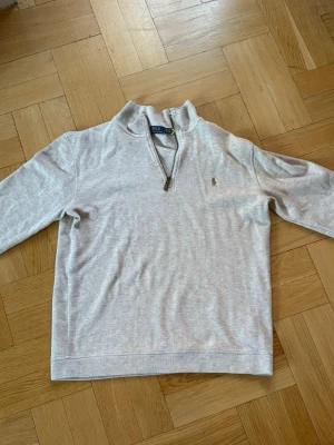 Half zip Polo Ralph Lauren - Ljusgrå stickad tröja från Polo Ralph Lauren med halv dragkedja och broderad logga på bröstet. Tröjan har lång ärm, ribbade muddar och hög krage. Perfekt för nu i hösten! Vid frågor och funderingar kan ni bara skriva ✍️!