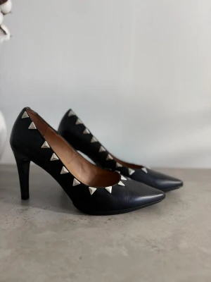 Svarta pumps med nitar från Hispanitas - ✨ Elegant och uttrycksfull modell från spanska Hispanitas 🥂 Perfekta för fest, middag, dejt eller andra speciella tillfällen 🖤 Spetsig tå och silverfärgade nitar 🔥 Exklusiv design med en elegant och rockig känsla 🎈Äkta skinn både utvändigt och invändigt 👠 Varken tåpartiet eller klackarna är nedslitna 🏷️ Nypris cirka 1 400 kr 📏 Storlek 39