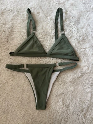 Bikini - Grön triangel bikini med runda metall detaljer. Justerbara axelband. 