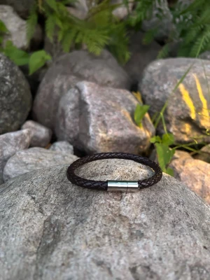 Flätat brunt läderarmband - Snyggt armband i mörkbrunt flätat läder med ett stilrent magnetlås i silverfärgad metall. Perfekt accessoar för dig som gillar en enkel men trendig look. Passar både till jeans och skjorta.