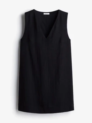 Svart ärmlös kort klänning - Stilren svart klänning med v-ringning och ärmlös design. Klänningen har en rak passform och kort längd, vilket ger en enkel och modern look. Perfekt att styla med accessoarer för en personlig touch. Använts 1 gång, skriv för fler bilder