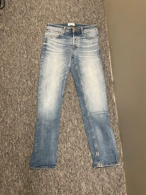 Blå slim fit jeans med slitningar - Snygga blå slim fit jeans med ljusa slitningar och klassisk femficksdesign. Jeansen har normal midja, dragkedjegylf och är tillverkade i ett mjukt denimtyg som ger en bekväm känsla. Perfekta för en avslappnad och trendig stil. Storlek 28/32