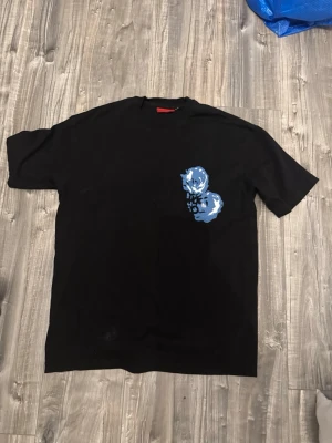 Svart HUGO t-shirt med blommor - Jätte fin och unik Hugo t shirt, sitter jätte bra och perfekt för att sätta outfiten till sin fulla potensial. Storlek M. Tyvärr lite för stor för mig.