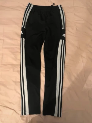 Svarta Adidas mjukisbyxor med ränder - Byxorna har resår i midjan och dragkedja vid bensluten. De är lite slitna men perfekt för att göra till shorts till exempel.
