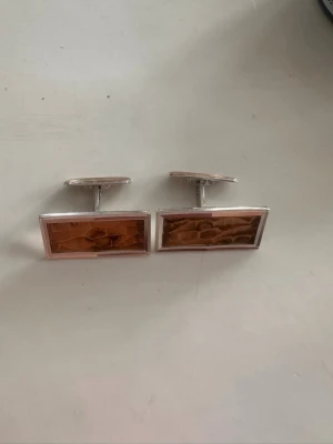 Manschettknappar i silver 835 - vintage - Par manschettknappar i silver med rektangular form och dekorativ front i brun ton. Stämplade med 835, Tre kronor i en oval samt S, vilket bekräftar att det är äkta silver. Skick: Begagnat men nästan nyskick Säljes som par Passar både till användning och för samlare av äldre silverföremål. Samfrakt erbjuds vid köp av flera saker - se garna mina andra annonser.