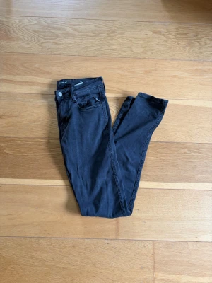 Svarta skinny jeans från Replay - Säljer ett par mörk grå skinny jeans från Replay i modellen anbass med klassisk femficksmodell och dragkedjegylf. Jeansen har smal passform och är tillverkade i stretchigt material för extra komfort. Perfekta för en trendig och avslappnad stil.