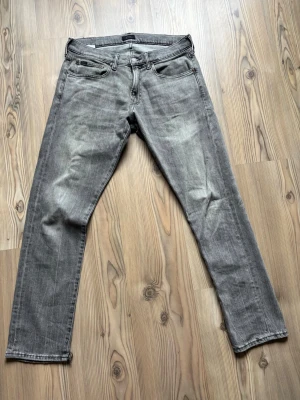 Grå raka jeans från Ralph lauren - Säljer ett par grå jeans med raka ben och klassisk femficksmodell. Jeansen har en snygg tvättad look med diskreta slitningar och normal midja. Materialet är denim i bomull och passformen är avslappnad men ändå stilren. Två små jack i byxöppningarna men lätt fixat.