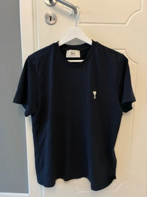 Ami Paris T-shirt  - Mörk blå ami Paris Tshirt, i mycket bra skick använd några gånger men blev för liten. Storleken är S och tröjan är äkta. Ny pris är typ 1000kr mitt pris är 350kr det är bara höra av dig vid funderingar.