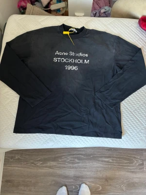 Acne studios tröja - Svart långärmad topp från Acne Studios med tryck 'STOCKHOLM 1996' framtill. Klassisk rund halsringning och relaxed fit. 10/10 skick och riktigt fet nu när det börjar bli kallare. 